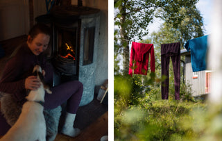 Kvinne i ullundertøy koser med en hund foran vedovnen, og ullplagg henger til lufting på en snor ute
